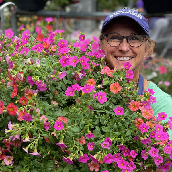 person with a large hanging basket of pink and red flowers